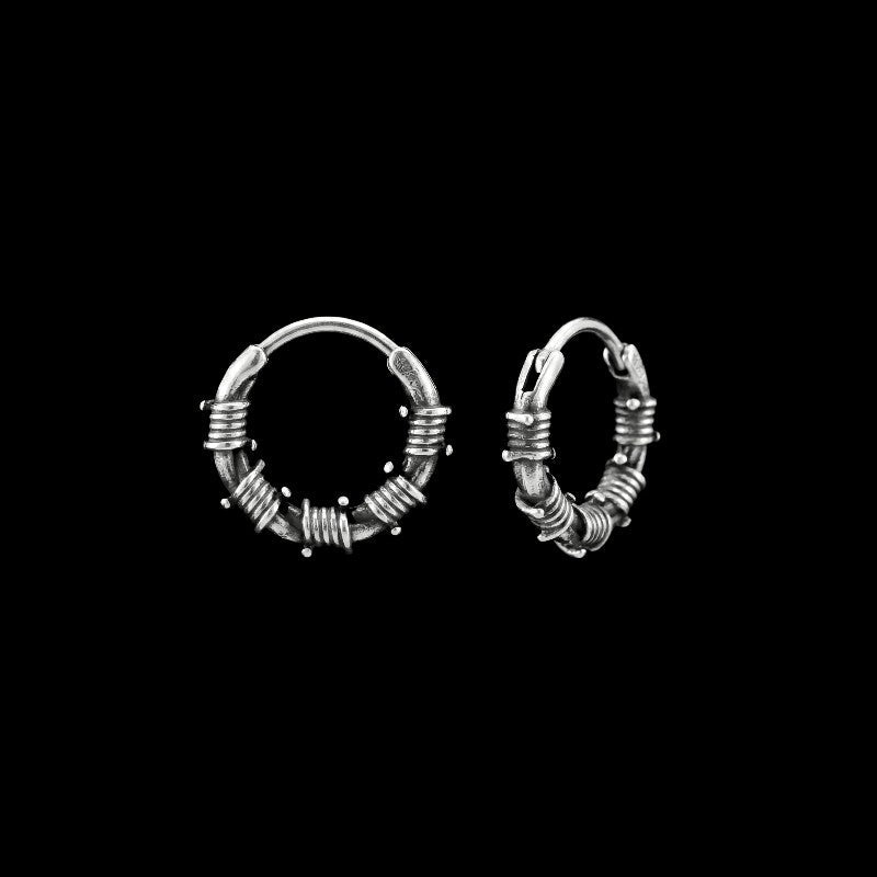 Barbed wire stainless steel hoop earrings on a black background