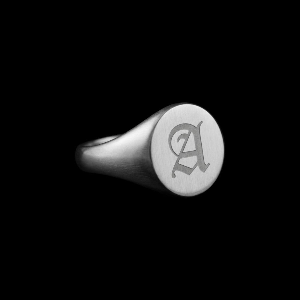 Custom circle signet stainless steel ring on a black background