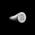 Custom circle signet stainless steel ring on a black background