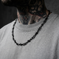 Black barbed wire stainless steel necklace on a black background